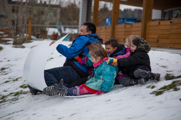 des enfants jouent dehors dans la neige avec un éducateur