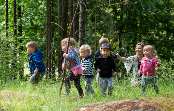 un groupe d’enfants avec une éducatrice explorent la forêt