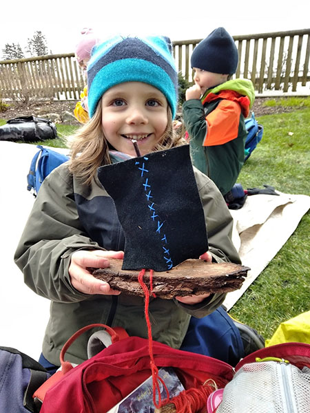 Child showing the finished boat assembled with wood and forest glue