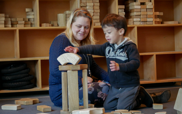 educator with young child playing with building blocks