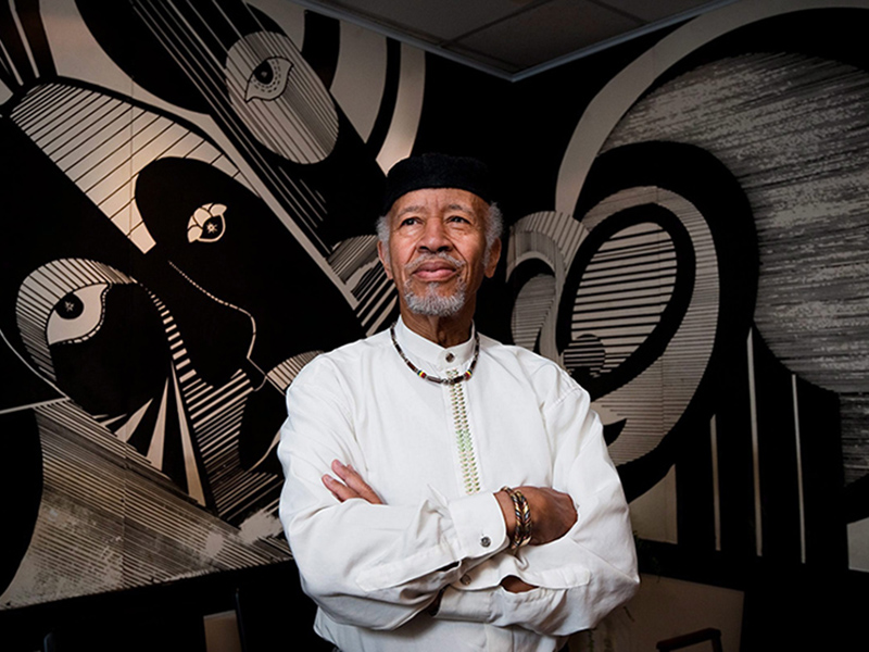 Image 14: Headshot of Charles Roach with large modern painting in background.