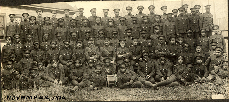 Historical sepia tone photo of a large group of Black soldiers in uniform.